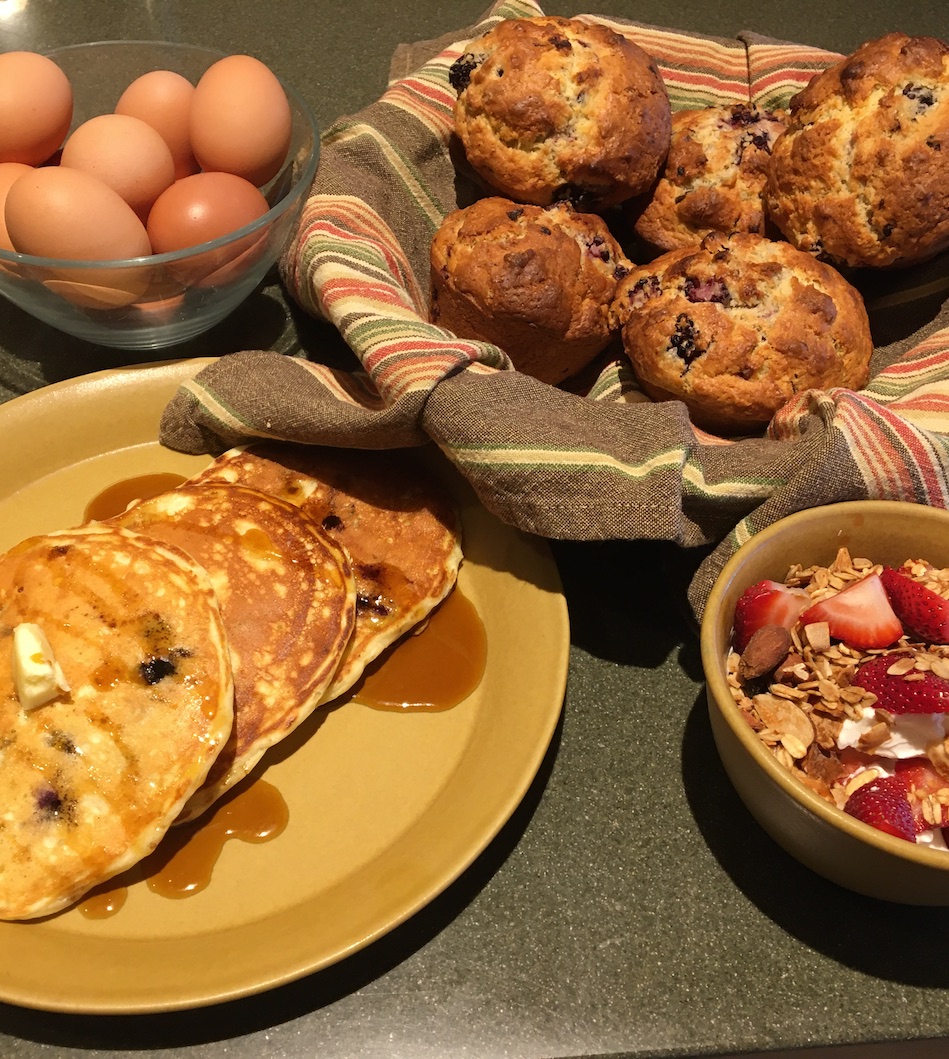 blueberry muffins, pancakes, fresh eggs, granola with strawberries and yogurt